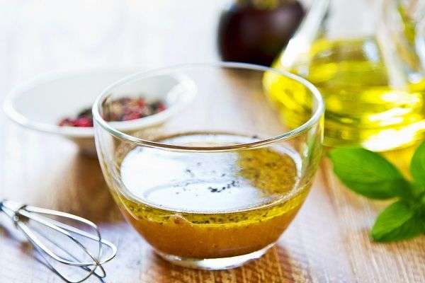 Cuenco transparente con salsa sobre tabla de madera con especias y aceite de oliva. 